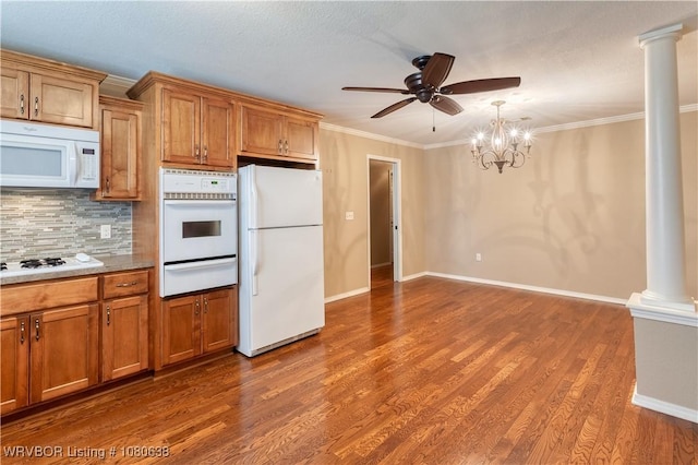 kitchen with brown cabinetry, white appliances, ornate columns, ceiling fan with notable chandelier, and a warming drawer