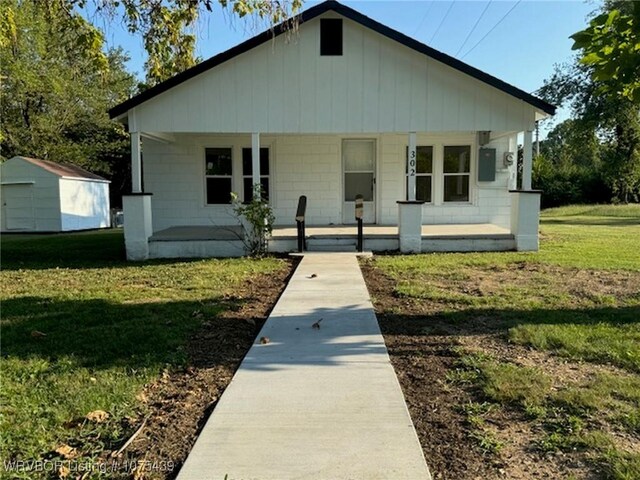 bungalow-style house with a front yard, covered porch, and a storage shed