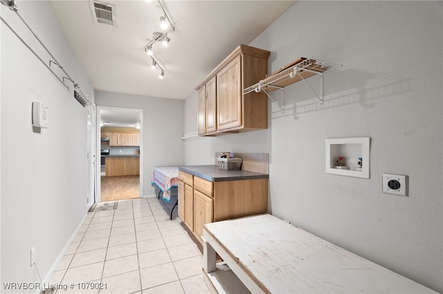 clothes washing area with light tile patterned floors, electric dryer hookup, hookup for a washing machine, cabinets, and track lighting