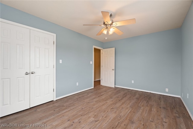 unfurnished bedroom with hardwood / wood-style floors, ceiling fan, and a closet