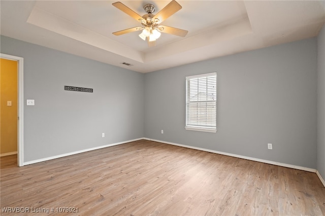 unfurnished room featuring ceiling fan, a tray ceiling, and light hardwood / wood-style flooring