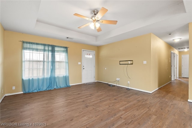 unfurnished room featuring hardwood / wood-style floors, a raised ceiling, and ceiling fan