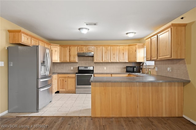 kitchen featuring appliances with stainless steel finishes, backsplash, light brown cabinetry, and kitchen peninsula