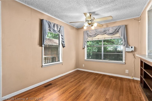 empty room with hardwood / wood-style flooring, ceiling fan, and a textured ceiling