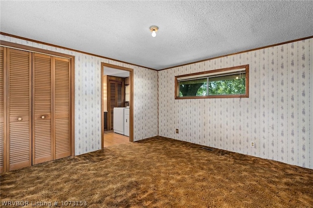 unfurnished bedroom featuring a textured ceiling, light colored carpet, washer and clothes dryer, crown molding, and a closet