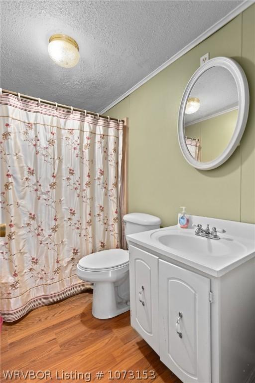 bathroom with vanity, wood-type flooring, a textured ceiling, and ornamental molding