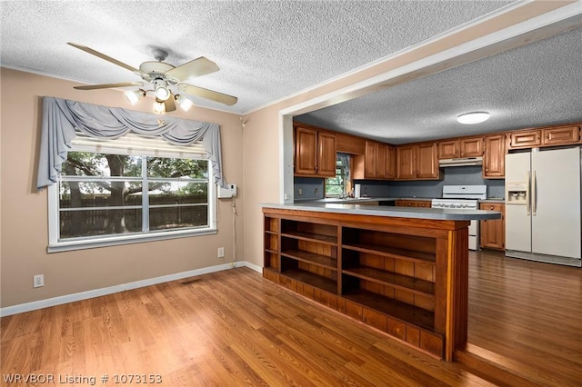 kitchen with white appliances, sink, ceiling fan, light wood-type flooring, and kitchen peninsula