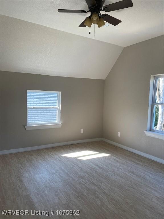 additional living space featuring hardwood / wood-style flooring, ceiling fan, and lofted ceiling