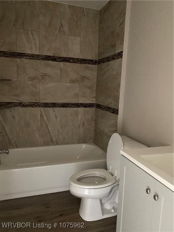 full bathroom with hardwood / wood-style flooring, vanity, toilet, and tiled shower / bath