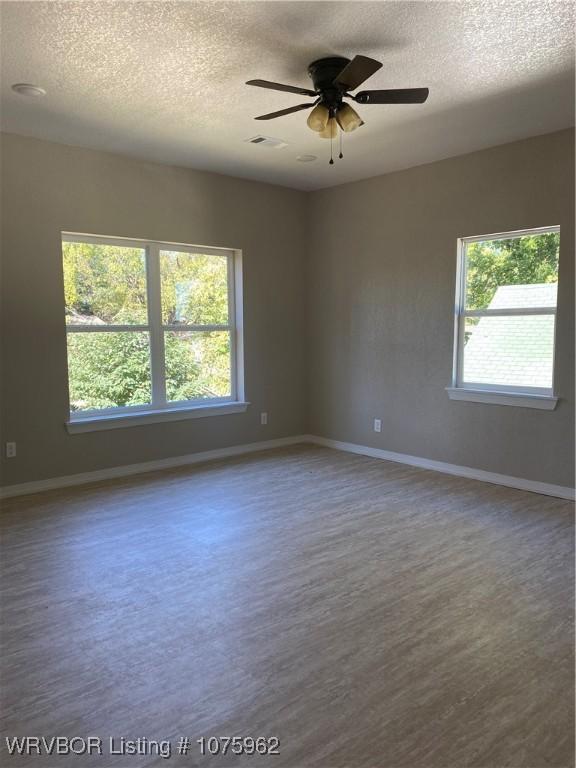 spare room featuring hardwood / wood-style flooring, ceiling fan, and a textured ceiling