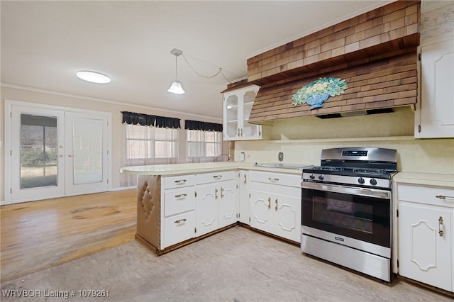 kitchen featuring light countertops, stainless steel range with gas stovetop, a peninsula, and white cabinetry