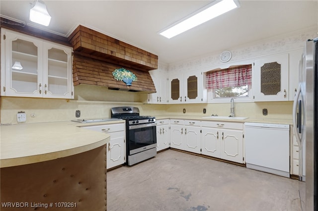 kitchen with light countertops, appliances with stainless steel finishes, white cabinetry, a sink, and concrete floors