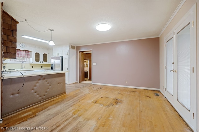 kitchen featuring a peninsula, light wood-style flooring, ornamental molding, and stainless steel fridge with ice dispenser