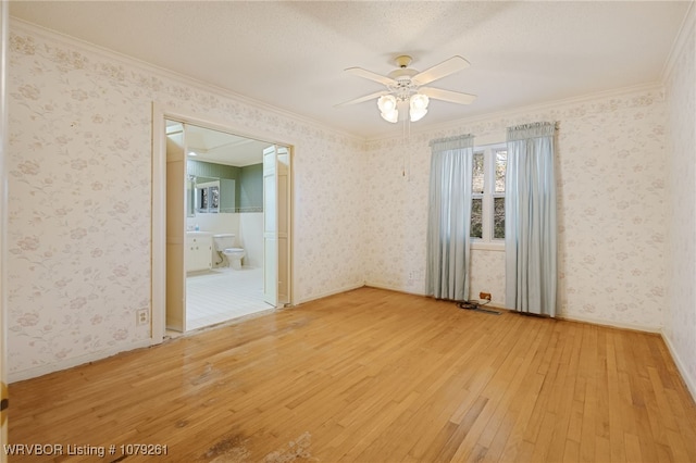 unfurnished room featuring baseboards, ornamental molding, wood-type flooring, and wallpapered walls