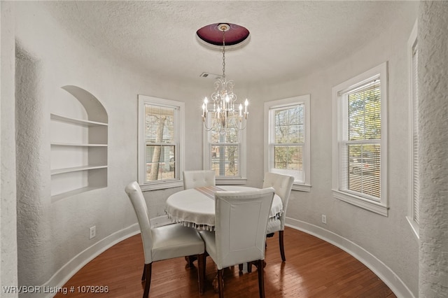dining area featuring baseboards, a textured wall, hardwood / wood-style floors, a textured ceiling, and built in shelves