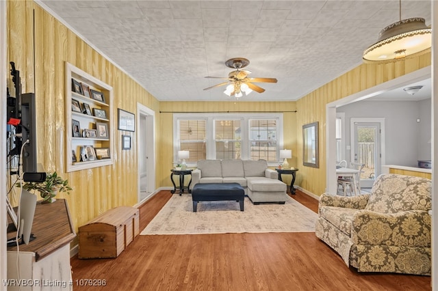 living room featuring built in features, a wealth of natural light, wood walls, and wood finished floors