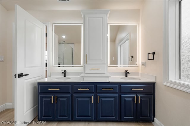 full bathroom with double vanity, baseboards, and a sink