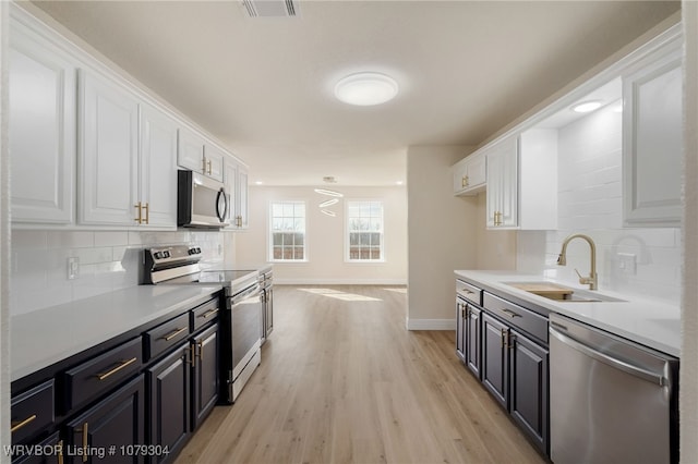 kitchen featuring stainless steel appliances, white cabinetry, a sink, and visible vents