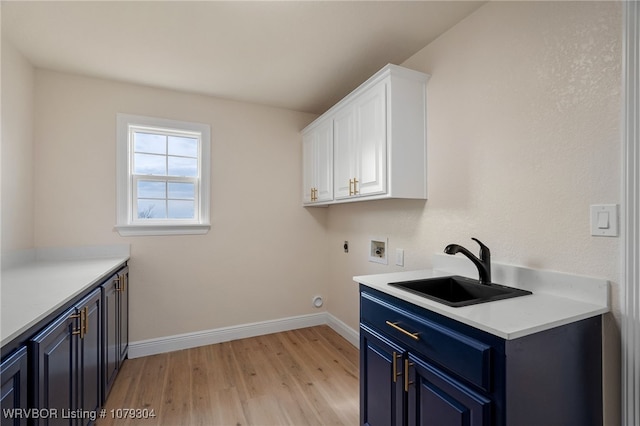 laundry room with washer hookup, cabinet space, light wood-style floors, a sink, and baseboards