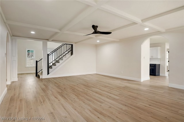 unfurnished living room featuring stairs, light wood finished floors, coffered ceiling, and arched walkways