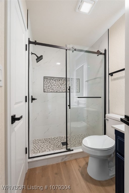 full bath with toilet, a marble finish shower, wood finished floors, and vanity