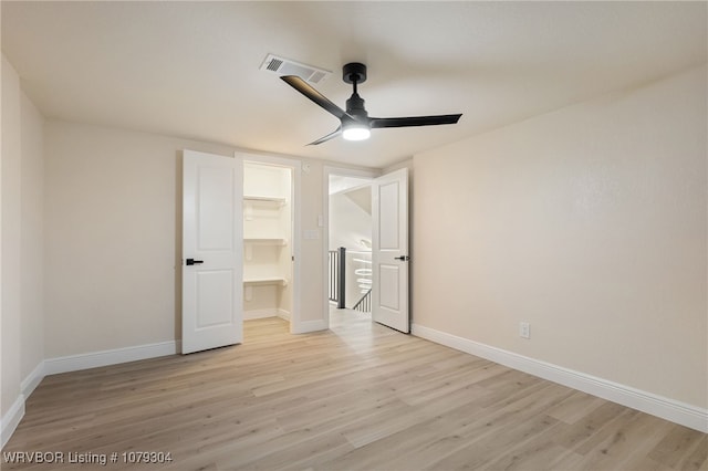 unfurnished bedroom featuring visible vents, light wood-style flooring, a spacious closet, ceiling fan, and baseboards