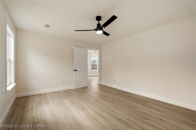 empty room with light wood-style floors, baseboards, visible vents, and ceiling fan