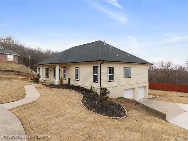 exterior space with a garage, driveway, a shingled roof, and fence