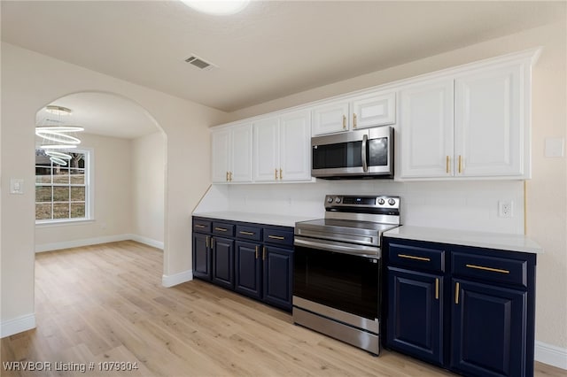 kitchen featuring stainless steel appliances, arched walkways, blue cabinets, and visible vents