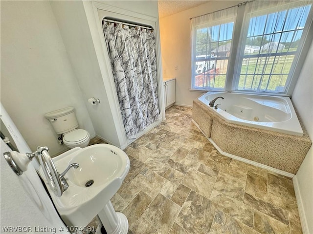 bathroom featuring tiled bath, toilet, and sink