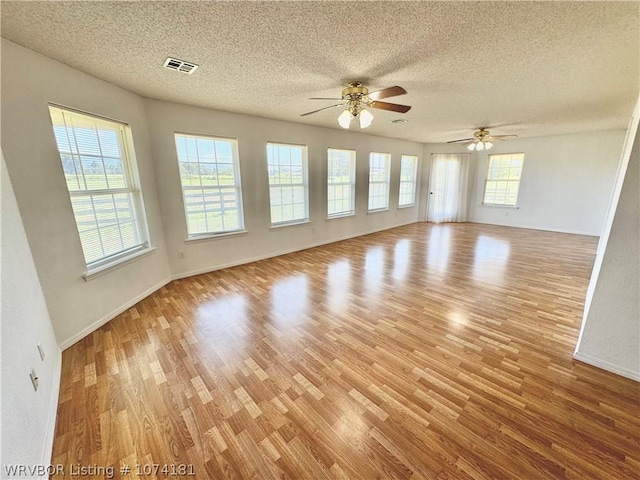 spare room featuring ceiling fan, light hardwood / wood-style floors, and a textured ceiling