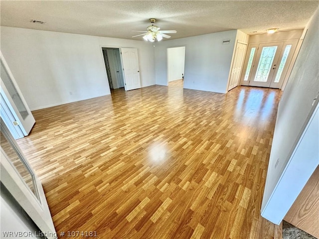 interior space with ceiling fan, a textured ceiling, and light hardwood / wood-style flooring