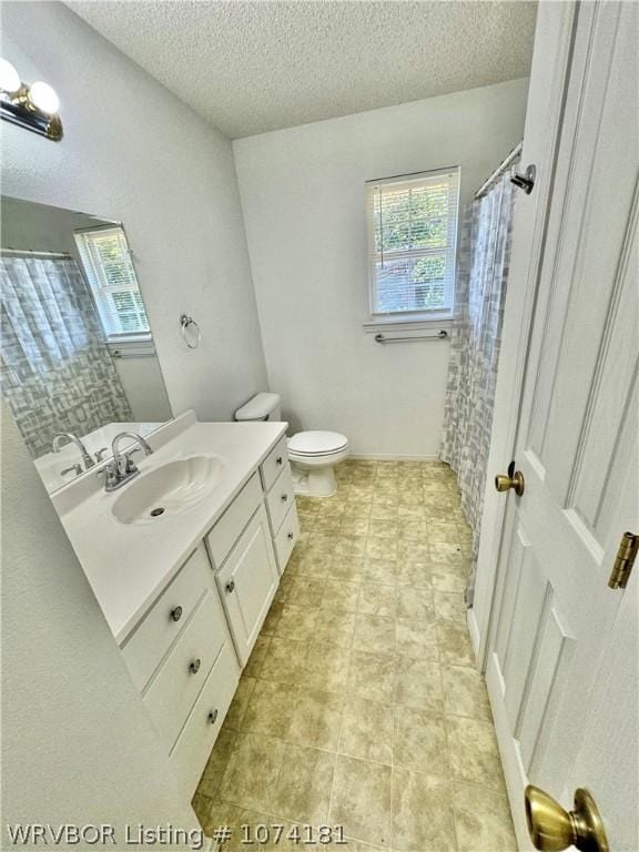 bathroom with a shower with shower curtain, a textured ceiling, vanity, and toilet