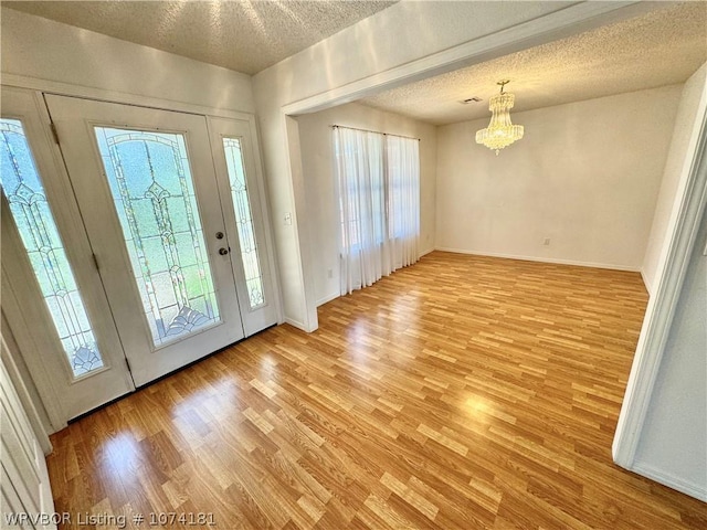 foyer entrance featuring a wealth of natural light, light hardwood / wood-style flooring, a chandelier, and a textured ceiling