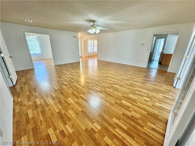 spare room with a textured ceiling, light hardwood / wood-style flooring, a wealth of natural light, and ceiling fan