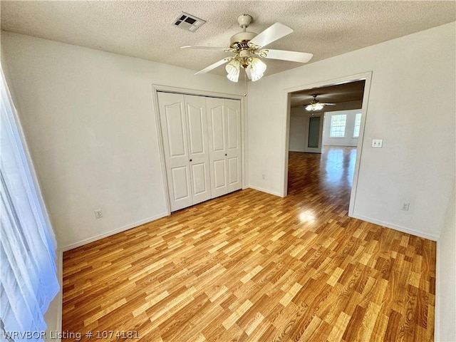 unfurnished bedroom featuring a closet, ceiling fan, light hardwood / wood-style flooring, and a textured ceiling