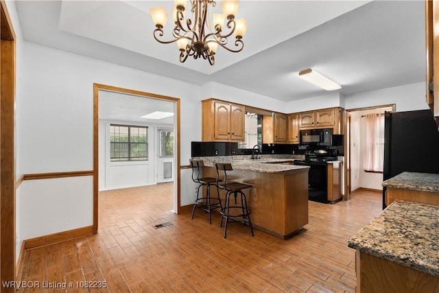 3017 Canongate Way, Fort Smith, AR 72908 - kitchen with black appliances, a peninsula, a chandelier, and light wood finished floors