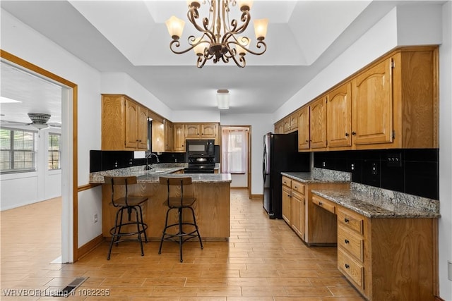 3017 Canongate Way, Fort Smith, AR 72908 - kitchen featuring black microwave, a peninsula, light wood-type flooring, range, and a breakfast bar