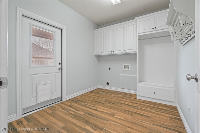 clothes washing area featuring electric dryer hookup, baseboards, hookup for a washing machine, cabinet space, and wood finished floors