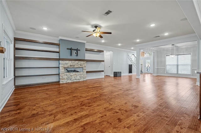 unfurnished living room with stairway, a fireplace, a ceiling fan, visible vents, and ornamental molding