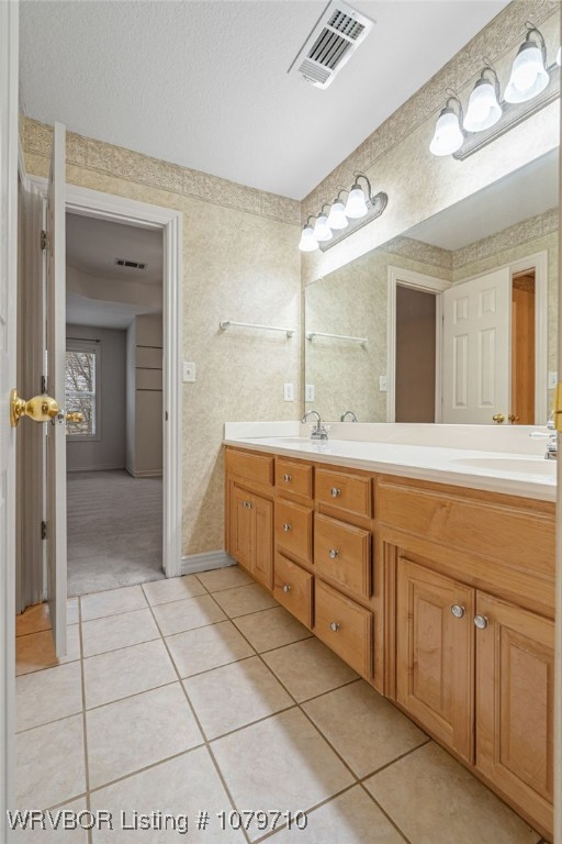 bathroom with a sink, tile patterned flooring, visible vents, and double vanity