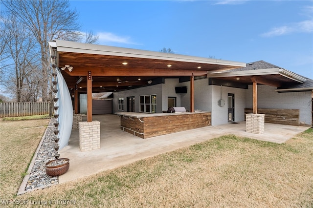 back of property with fence, outdoor dry bar, a patio, and brick siding
