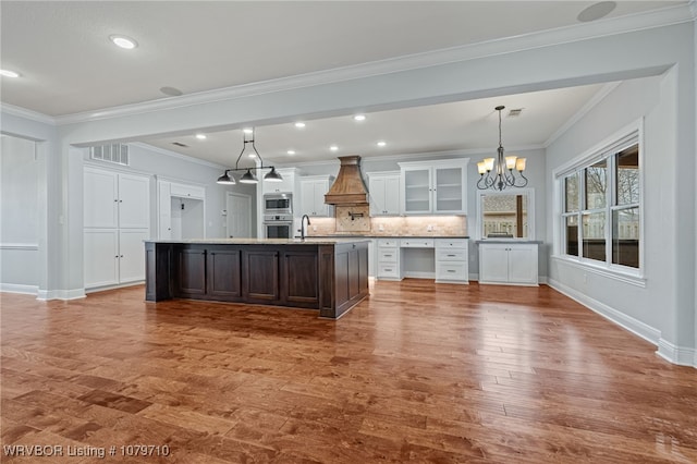 kitchen featuring an inviting chandelier, wood finished floors, stainless steel appliances, and crown molding