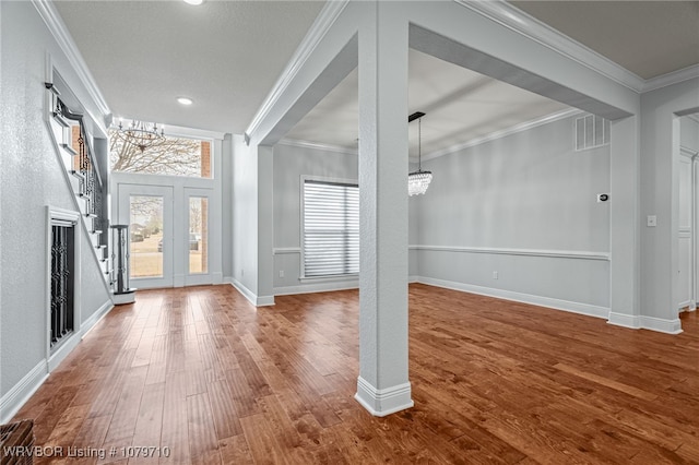 foyer with crown molding, a notable chandelier, stairway, and dark wood-style flooring