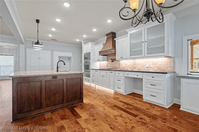 kitchen featuring decorative backsplash, custom range hood, appliances with stainless steel finishes, ornamental molding, and wood finished floors