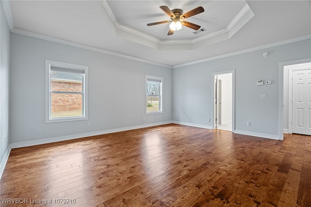 spare room featuring crown molding, visible vents, a tray ceiling, wood-type flooring, and a ceiling fan