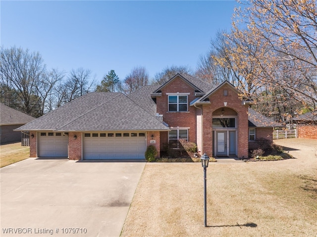 traditional home featuring concrete driveway, an attached garage, a shingled roof, and brick siding