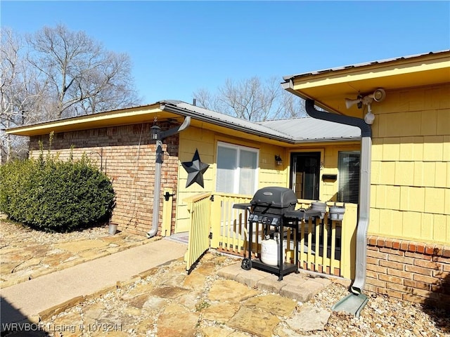 entrance to property featuring brick siding and metal roof