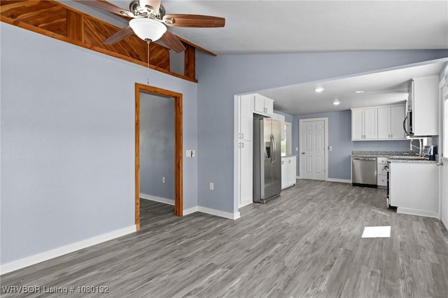 kitchen featuring a ceiling fan, baseboards, lofted ceiling with beams, light wood-style flooring, and stainless steel appliances