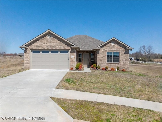 view of front of home with driveway, roof with shingles, an attached garage, a front lawn, and brick siding